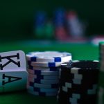 Close-up of two playing cards and stacks of poker chips on a green felt table